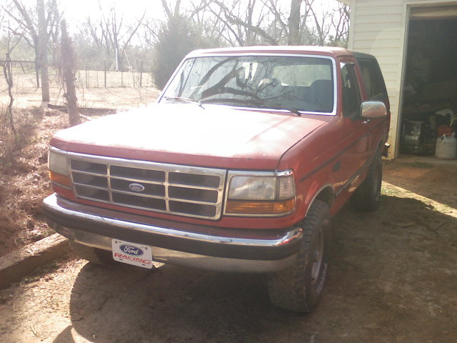 Red 1992 Ford Bronco parked in front of a garage