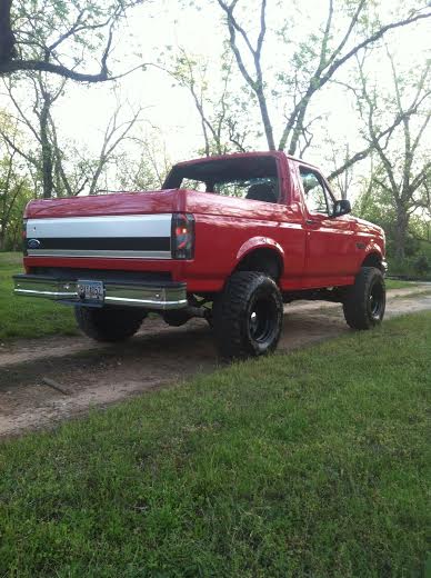 1992 Ford Bronco - This lifted 1992 Ford Bronco is shown from a 3/4 front angle, highlighting its large tires and off-road stance.