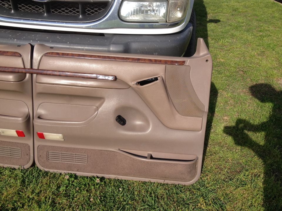 Tan interior door panels with wood trim, next to a vehicle grille