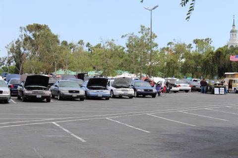 Line of sedans with open hoods, a domed tower visible in the distance