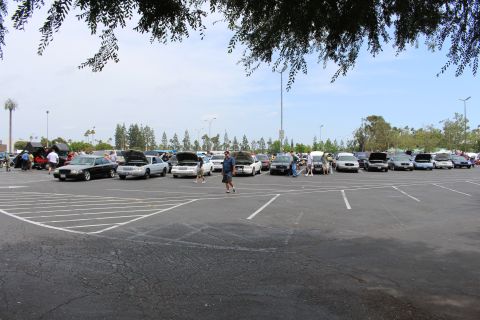 Distant row of cars with open hoods seen across an empty parking lot