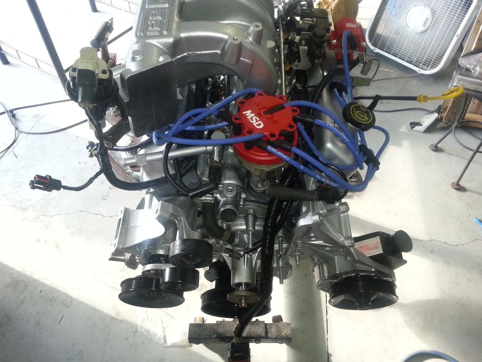 Engine assembly with MSD distributor and blue spark plug wires. Supermotors.net logo visible