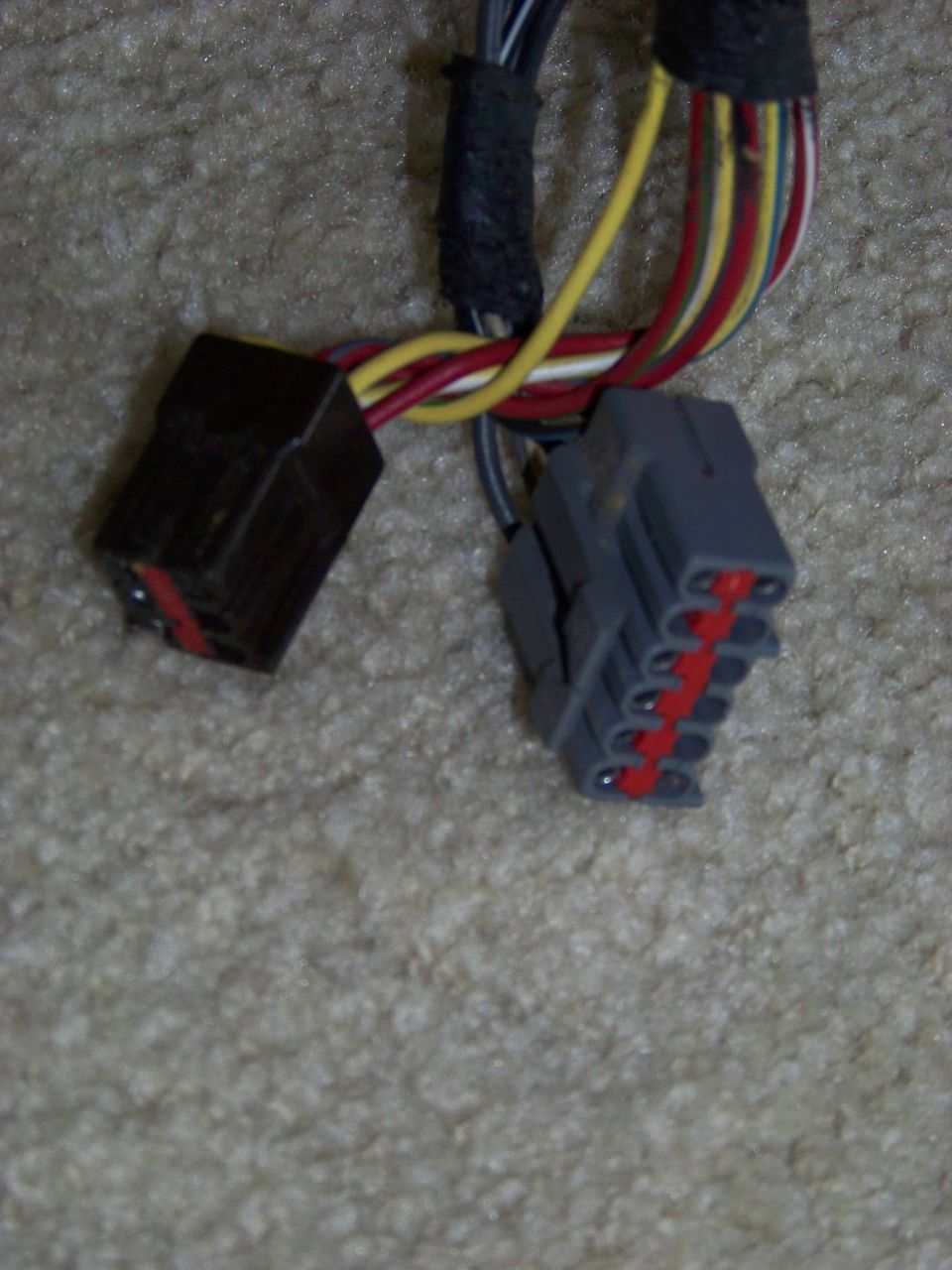 Two electrical connectors with colorful wires attached, resting on carpet