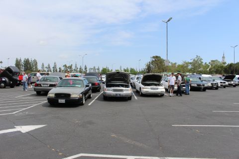 Two sedans facing camera with hoods open, people standing nearby