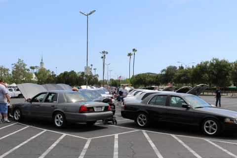 Gray and black sedans with raised hoods in a parking lot under a clear sky