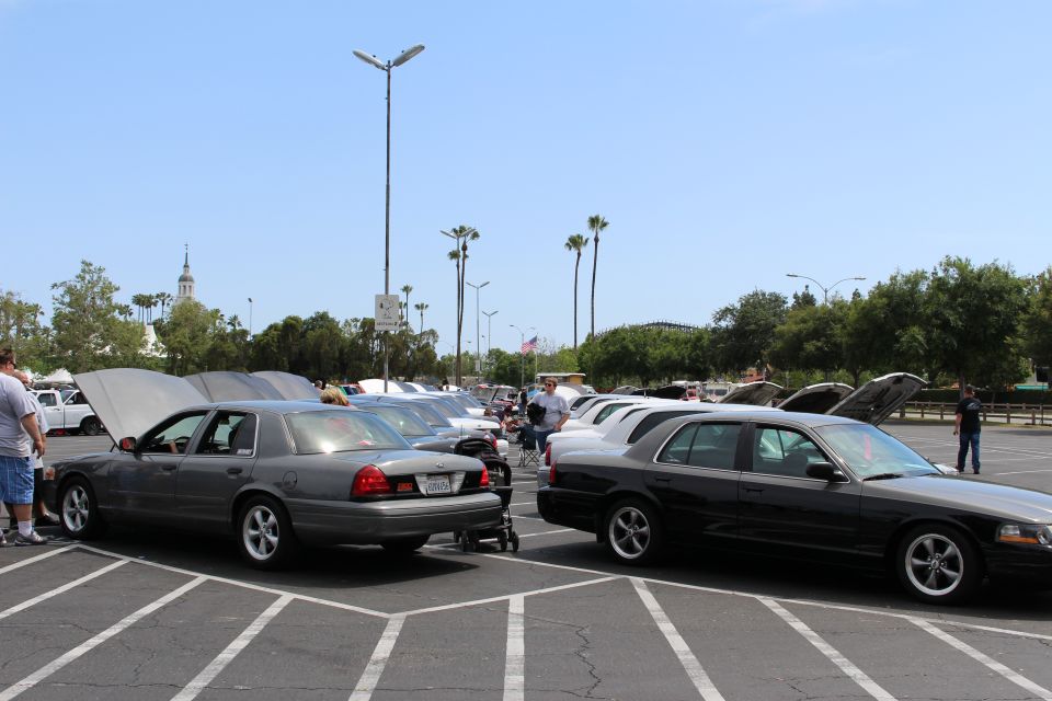 Gray and black sedans with raised hoods in a parking lot under a clear sky