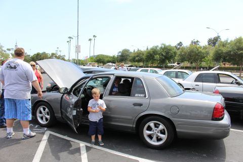 Gray sedan with hood up, a young boy standing by the open driver door