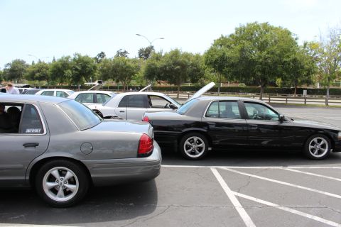 Rear three-quarter view of gray and black sedans parked side by side