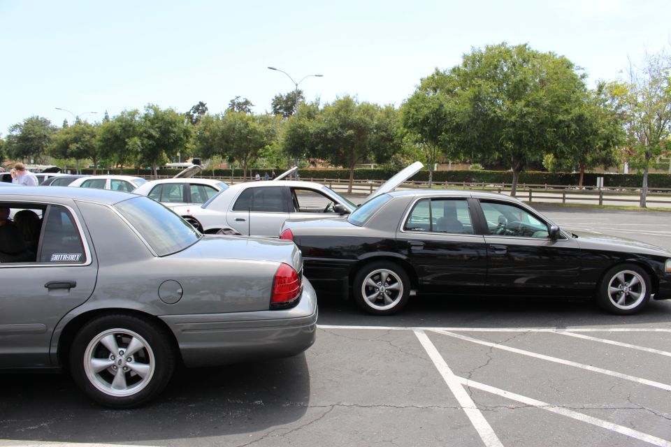 Rear three-quarter view of gray and black sedans parked side by side