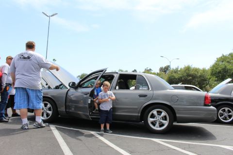 Gray sedan with hood up and open doors, two children and a man nearby
