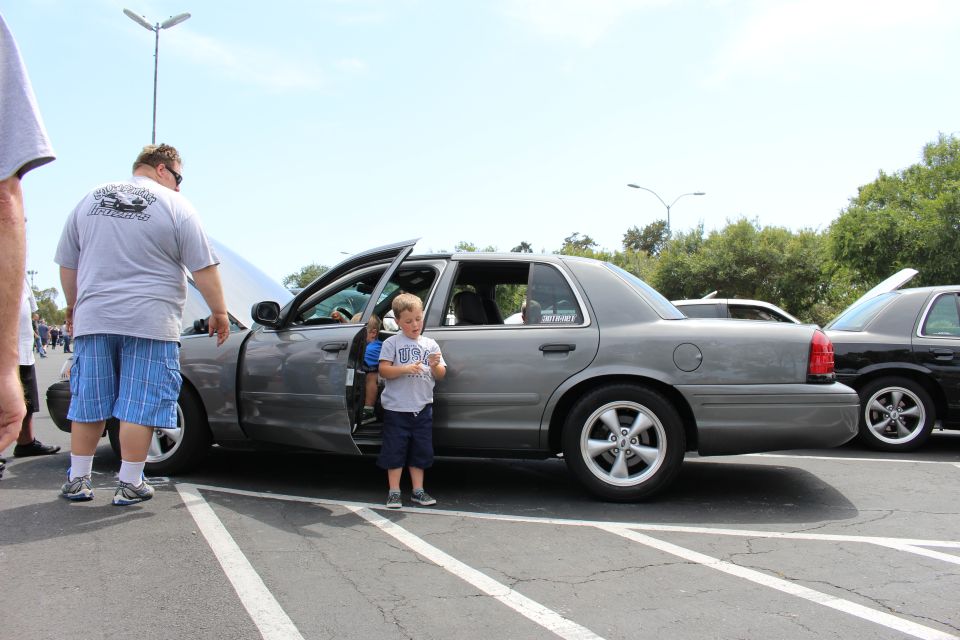 Gray sedan with open doors and a boy beside it, man leaning in the doorway