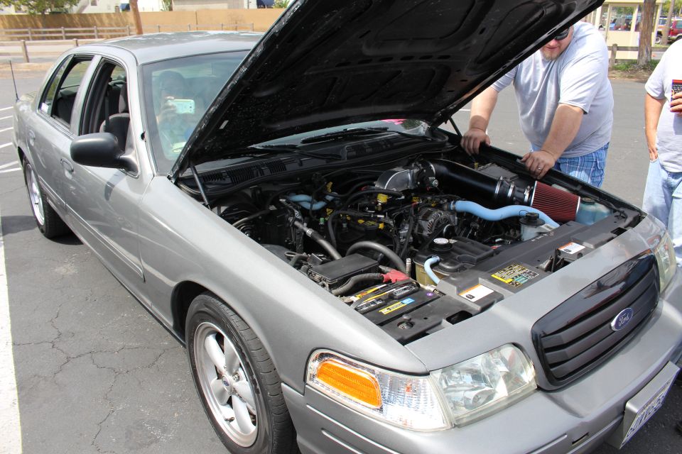 Silver Ford sedan with raised hood showing engine and red cone air intake