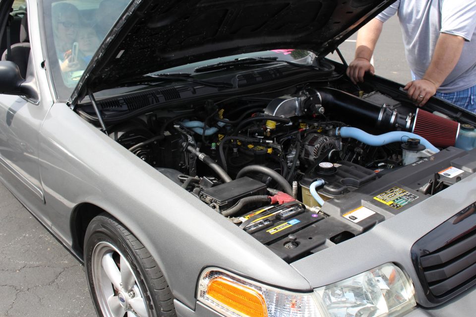 Close-up of a silver sedan's engine bay with red cone intake and blue hoses