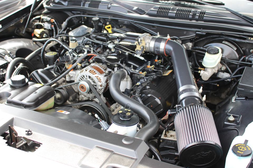 Close-up engine bay with black cone intake, master cylinder and wiring