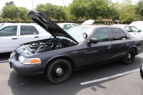 Dark gray sedan on black steel wheels with hood up in a parking lot