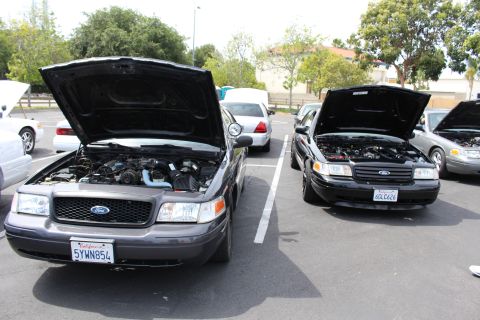 Two dark Ford sedans with raised hoods and visible California plates