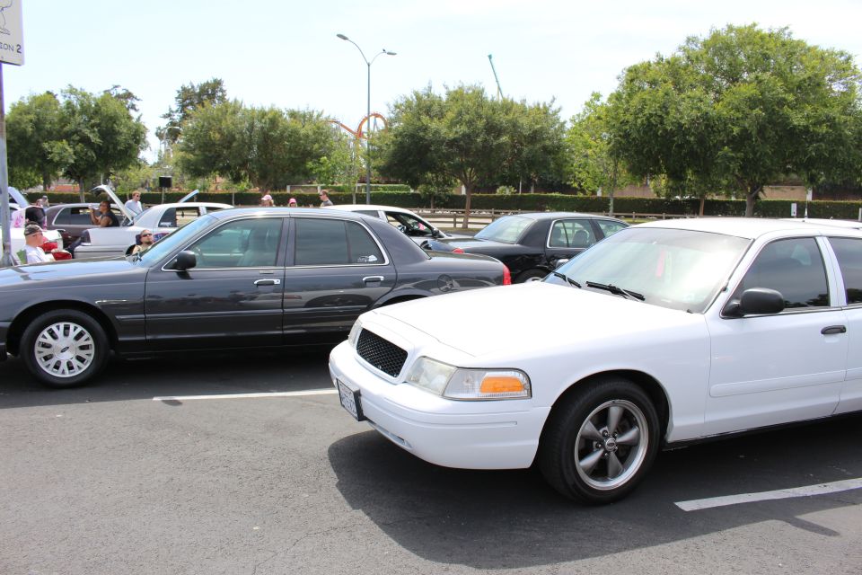 White Ford Crown Victoria and dark sedans parked at an outdoor car meet