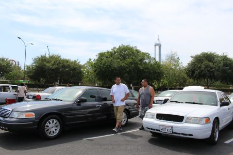 Dark and white full-size sedans with two men standing between them