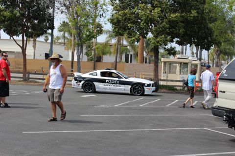 White and black Mustang-style coupe lettered POLICE driving in a lot