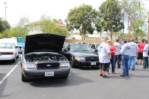 Dark Ford Crown Victoria with open hood and people gathered nearby