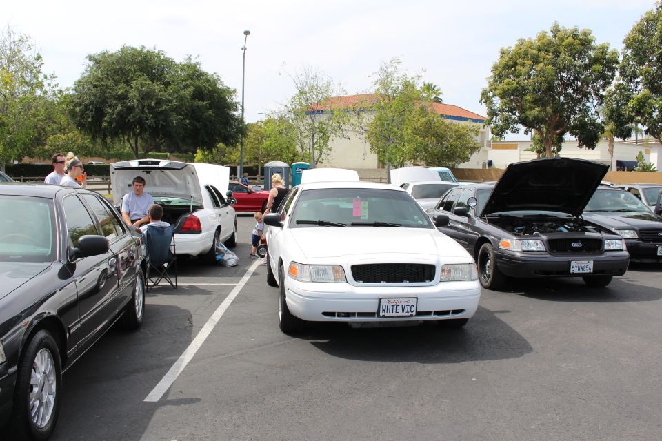 White Ford Crown Victoria centered between dark sedans in a parking lot