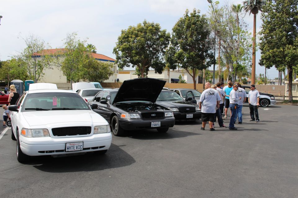 White and black Ford sedans with people gathered at an outdoor car meet