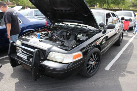 Black Crown Victoria sedan with hood up and push bar at a car show