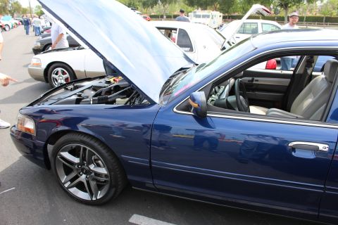 Front quarter of a blue sedan with open hood and gray wheels