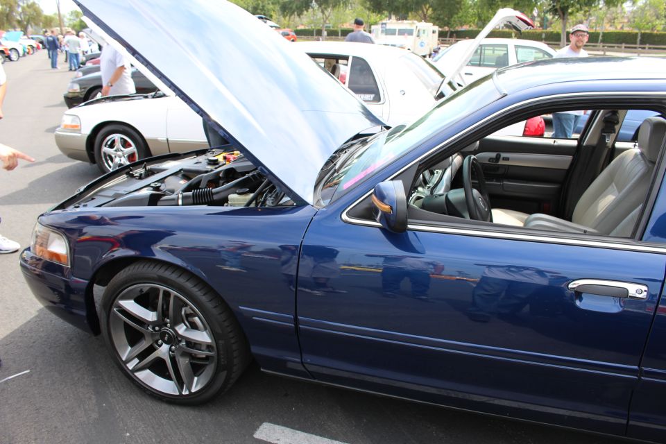 Front quarter of a blue sedan with open hood and gray wheels