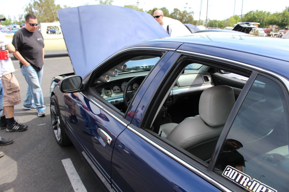 Side view of a blue sedan with open hood and gray interior