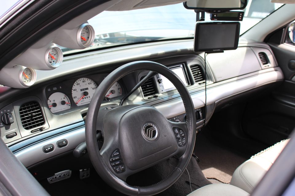 Driver area of a sedan with Mercury steering wheel and aux gauges