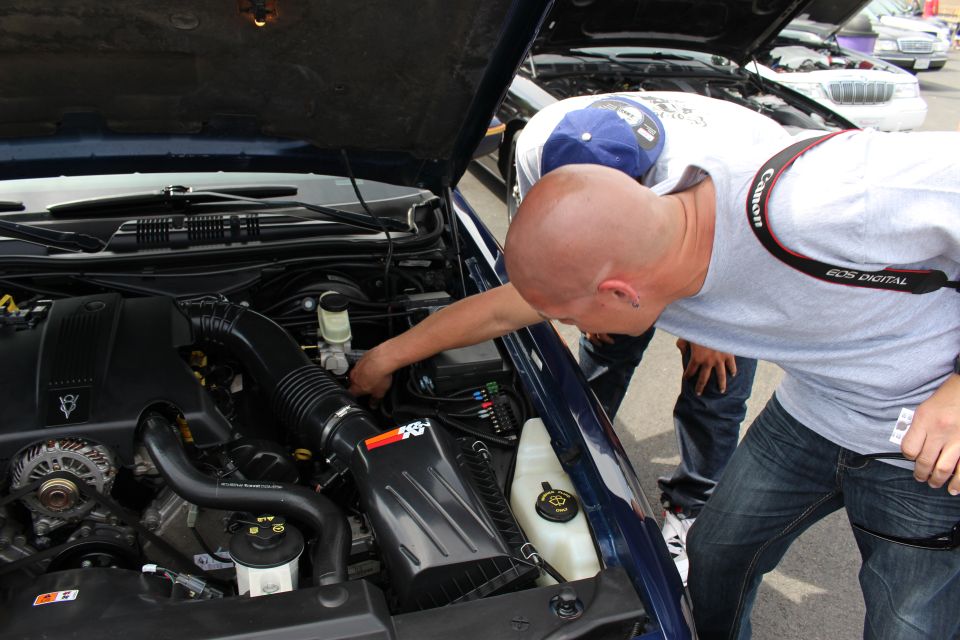 Man inspecting engine bay of a blue sedan with K&N filter