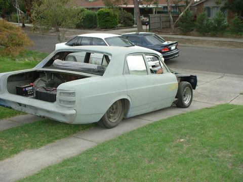 1970 Ford Falcon - This sedan is in primer, with its trunk open, revealing a battery and some wiring.