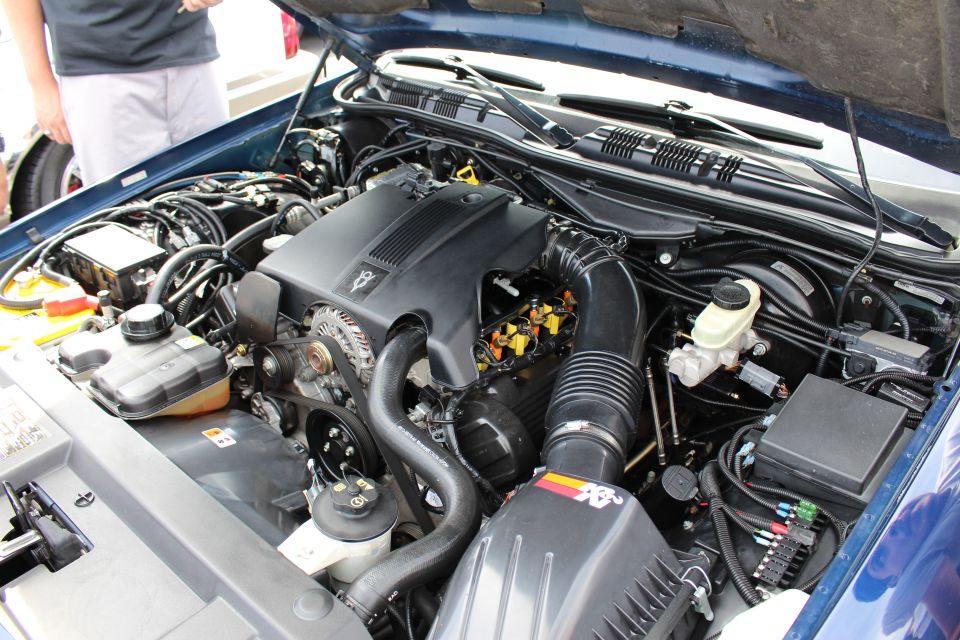 Engine bay of a blue sedan with K&N intake and Mercury cover