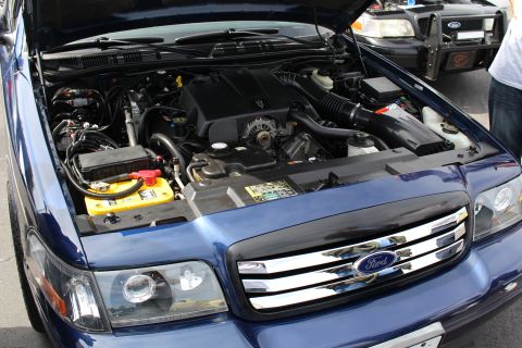 Engine bay of a blue Ford sedan with chrome grille