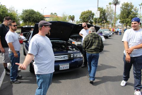 Car show crowd beside a blue Ford sedan with BLUE VIC plate