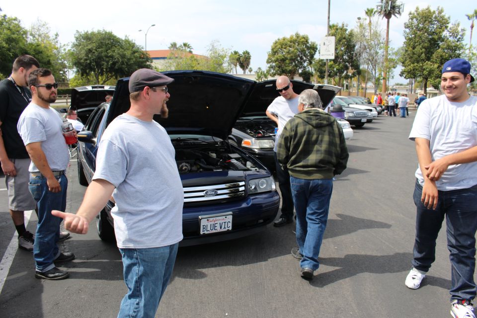 Car show crowd beside a blue Ford sedan with BLUE VIC plate