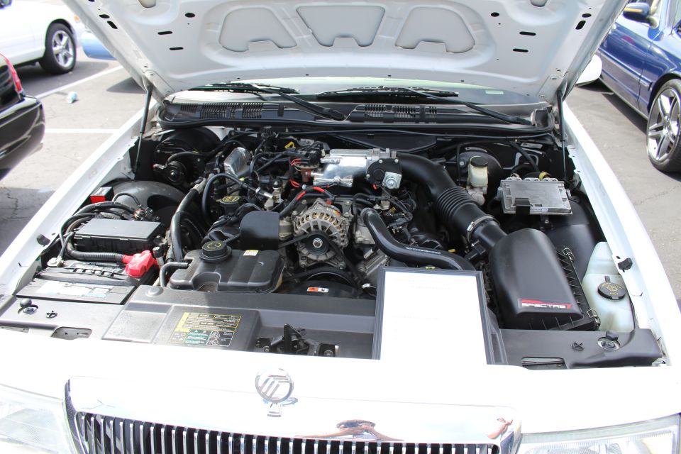 Engine bay of a silver Mercury sedan at a car show