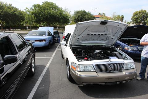 Champagne Mercury Grand Marquis with open hood among parked cars