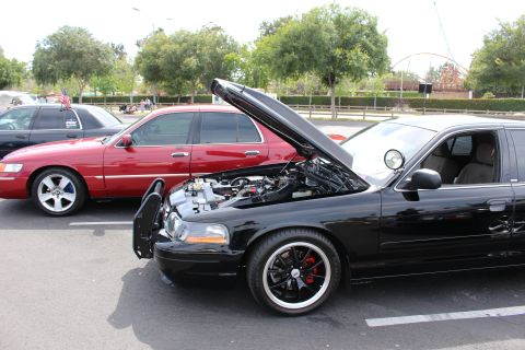 Black Mercury sedan with raised hood and black wheels beside a red car