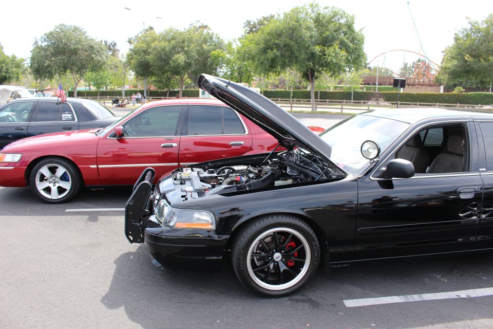 Black Mercury sedan with raised hood and black wheels beside a red car