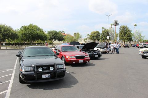 Black Ford police sedan with push bar beside a red Mercury sedan