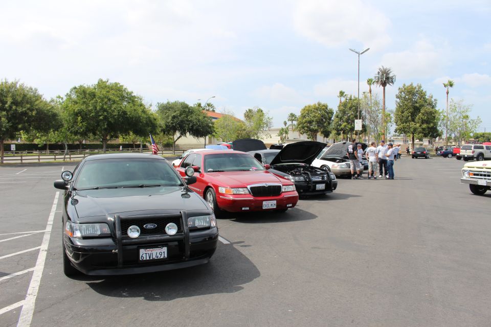 Black Ford police sedan with push bar beside a red Mercury sedan