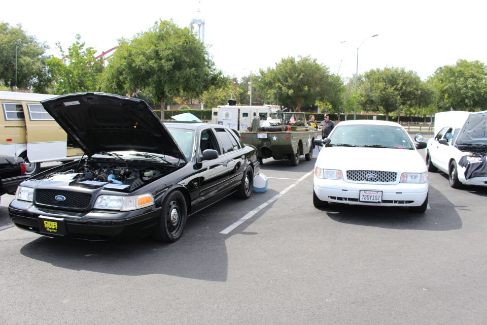 Black Ford Crown Victoria with open hood next to a white Ford sedan