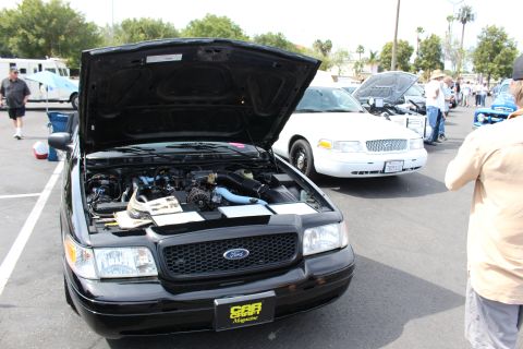 Black Ford sedan, hood up, with Car magazine plate at a show