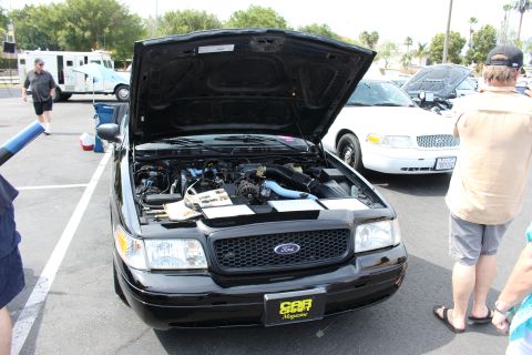 Black Ford sedan engine bay with Car Magazine plate, hood raised