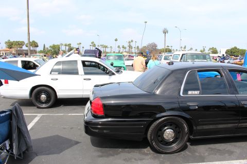 Black and white full-size sedans parked side by side at an outdoor car show