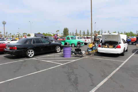 Black and white sedans with open trunks and folding chairs in a parking lot