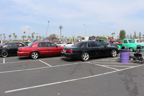 Red and black full-size sedans on chrome wheels parked in a sunny lot