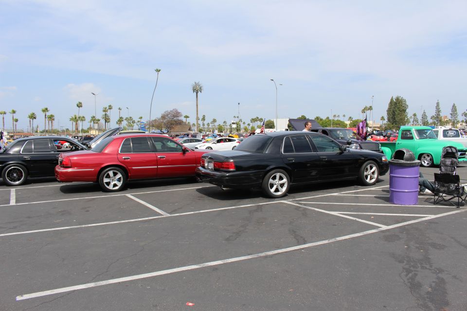 Red and black full-size sedans on chrome wheels parked in a sunny lot
